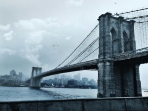 Scenic view of the iconic Brooklyn Bridge against a cloudy New York City skyline.