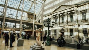 Sunlit atrium with statues and visitors at the Metropolitan Museum of Art, New York.
