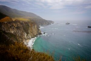 Stunning seascape of cliffs meeting the ocean under a cloudy sky in Soledad, California.