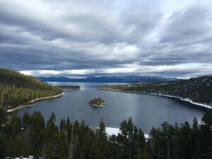 Breathtaking view of South Lake Tahoe with pine forests and dramatic clouds.